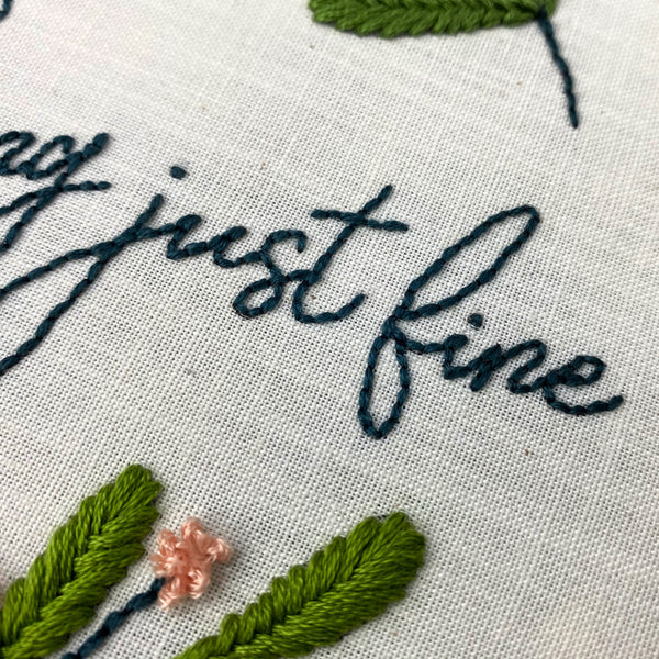 up close shot showing stitch work that says "just fine" and leaf detail