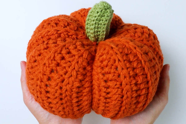 woman holding a crochet pumpkin
