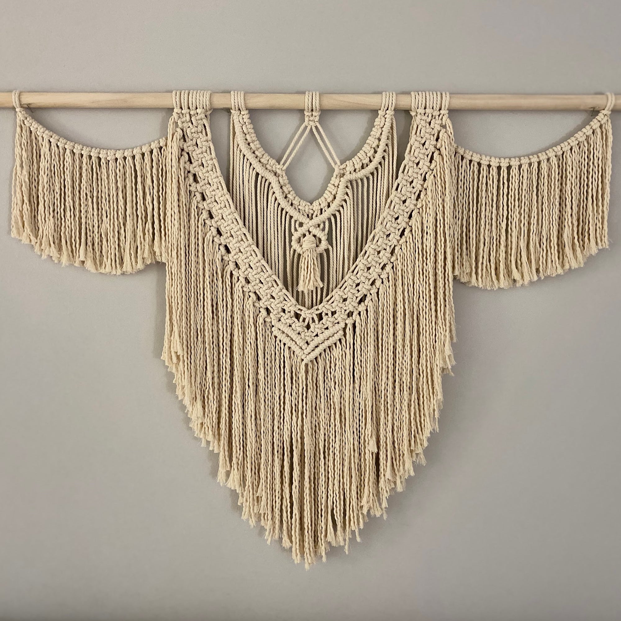 large macrame wall hanging against a light gray wall
