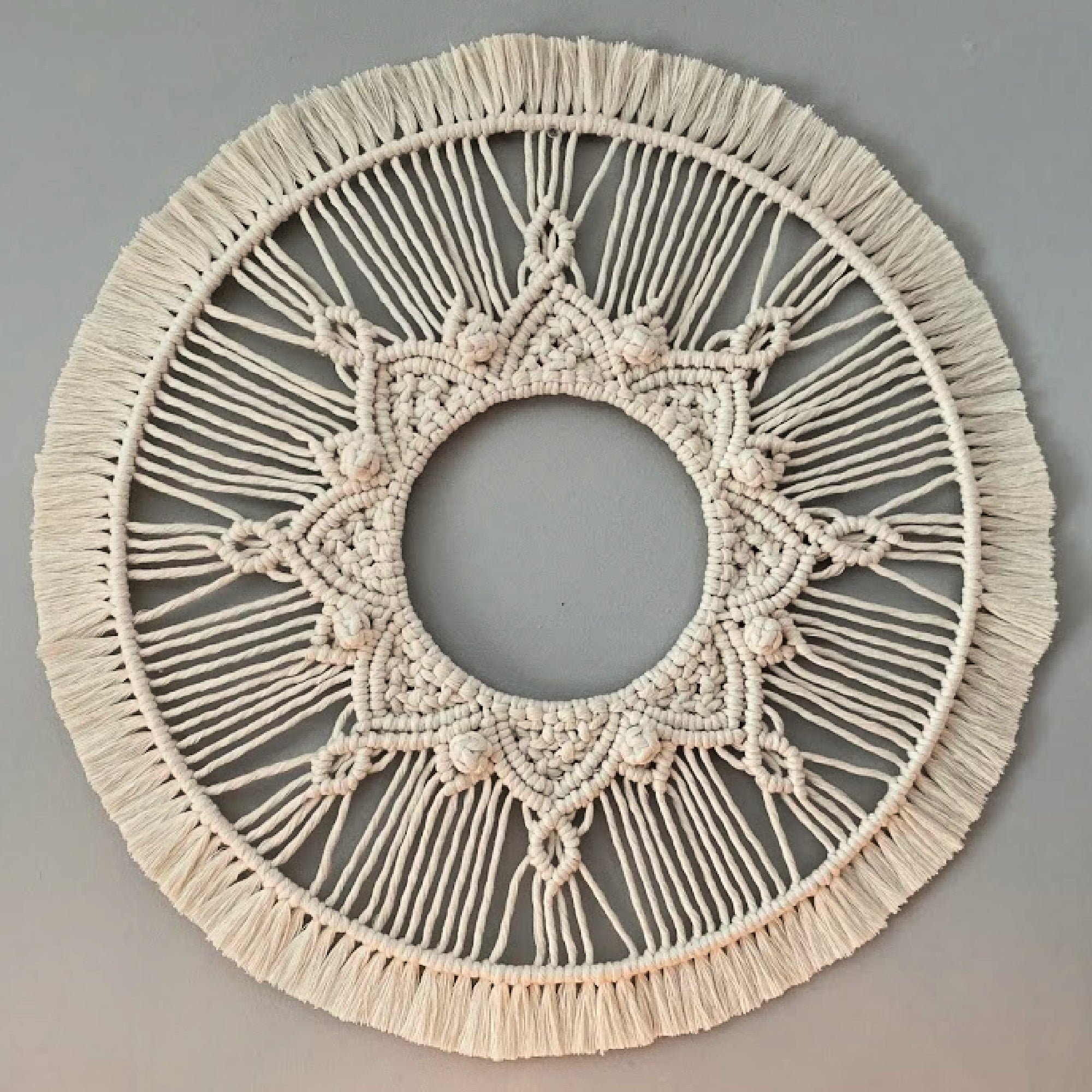 macrame mandala wall hanging on a light gray wall