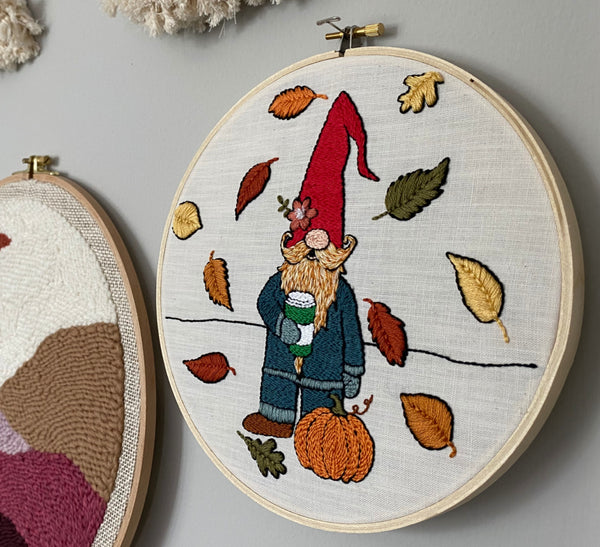 Finished Pumpkin Spice Pete embroidery hoop hanging on the wall at an angle